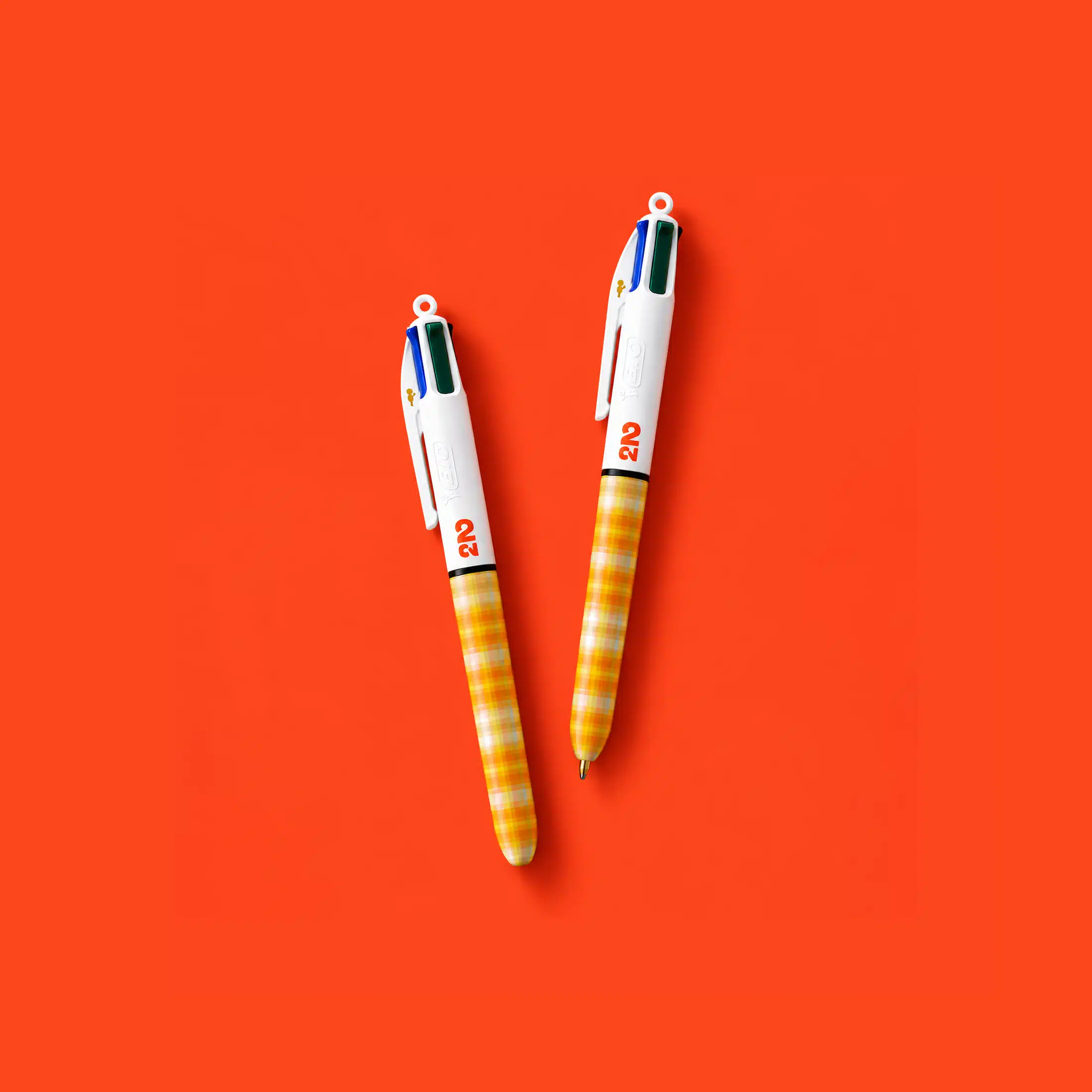 Two ballpoint pens with orange, yellow and white patterns and 2CV branding on an orange background
